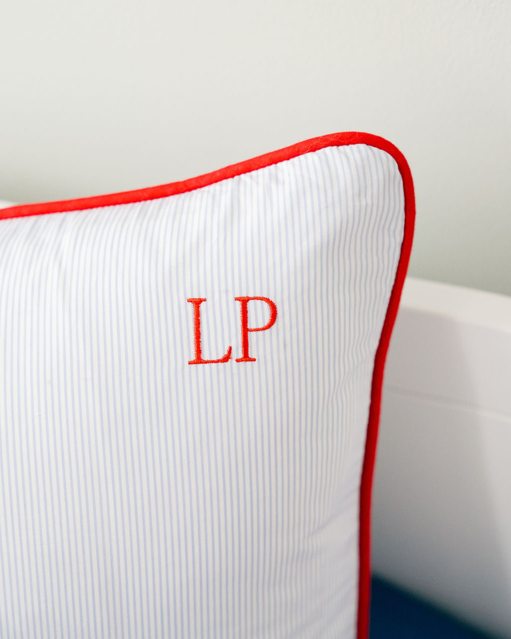 Blue pinstriped pillow with red piping and red embroidered LP initials